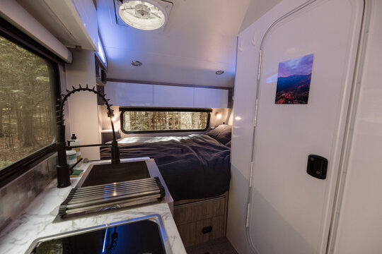 Compact interior of a camping trailer including bed and kitchen.