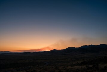 Fototapeta premium Desert landscape at dawn with mountains and orange horizon