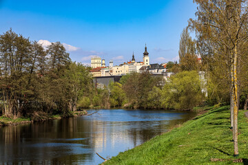 Obraz premium Picturesque river flows through a green landscape towards a historic European town