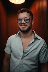 Fototapeta premium Smiling young man wearing sunglasses expressing happiness