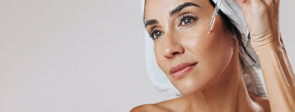 Skincare, thinking or mature woman with dropper in studio, apply hyaluronic acid or anti aging treatment. Banner, vision or person with hydration serum for skin glow, mockup space or white background