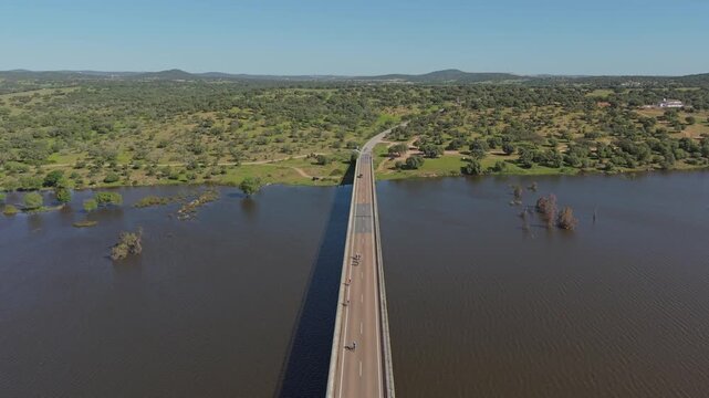 Drone shot of cyclists crossing bridge between Portugal and Spain over river in scenic landscape