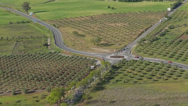 Aerial drone view of cycling race riders passing roundabout in rural landscape with winding road Portugal