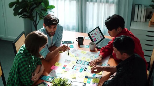 Top view of business team brainstorming idea by using mind map while putting hand together. People designing Ux Ui design for mobile phone while making stack of hands and clapping hand. Convocation.