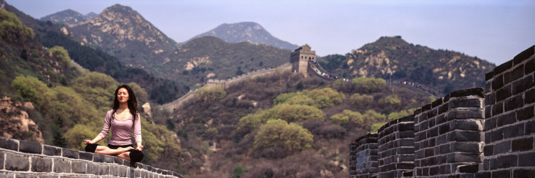 Woman meditating on The great wall of China