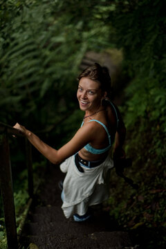 Cheerful woman holding railing on steep jungle trail stairs, Bali