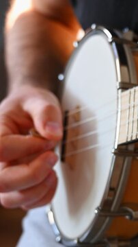 Close-up of Male Hand Picking Strings of Wooden Banjolele
