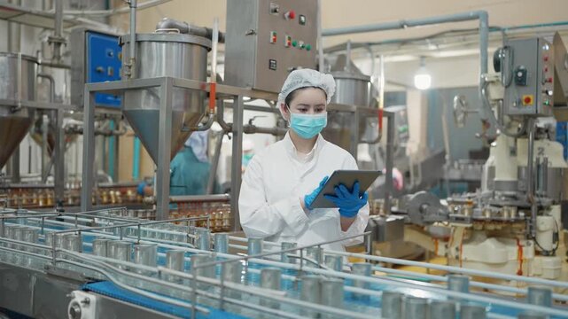 Precision in Production: A dedicated food processing plant worker meticulously monitors the automated canning line, ensuring impeccable quality control in a dynamic and efficient industrial setting.