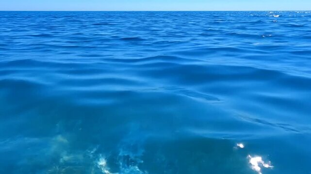 Scenic view of a tranquil blue ocean surface under a clear, cloudless sky with sparkling sunlight