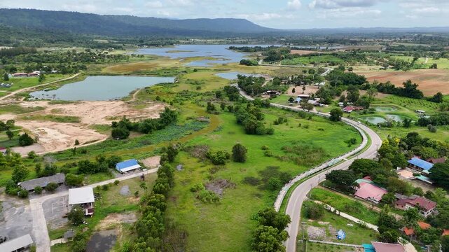 High-angle drone footage of a winding mountain road cutting through dense green forest, capturing natural landscape, scenic travel route, and peaceful countryside environment from above.