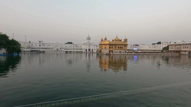 A serene wide shot of the iconic Golden Temple (Harmandir Sahib) in Amritsar during the blue hour. Reflecting the golden architecture and white marble buildings of the complex.