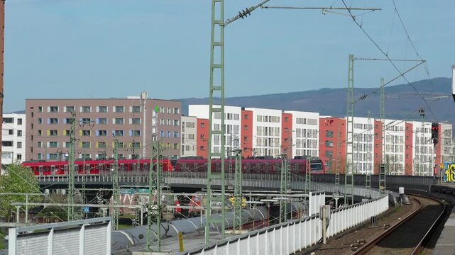 Long freight train moving through railway tracks in Frankfurt with residential buildings and infrastructure in background urban transport scene