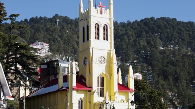 christ church shimla yellow gothic tower with cross and mountain forest background