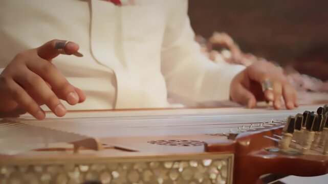 Close-up of hands playing a traditional Middle Eastern qanun, a stringed instrument commonly used in Saudi Arabian and Arabic music.