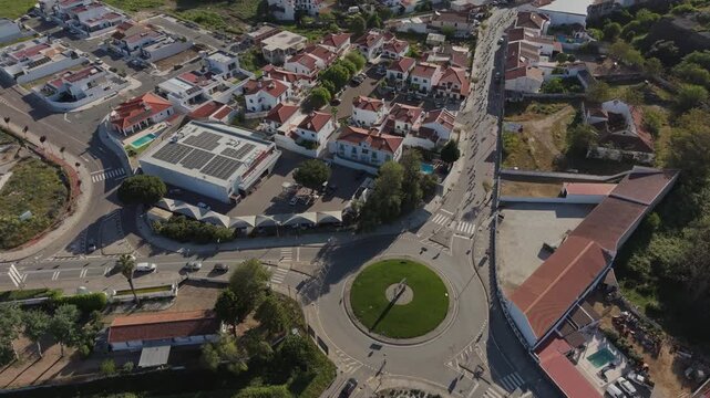 Drone shot of cycling race peloton moving through small town streets and roundabout