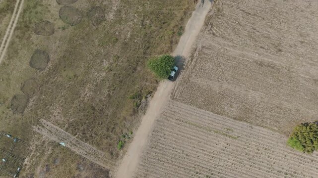 Aerial drone footage of car driving on rural road through countryside landscape, travel journey, transportation and scenic nature environment