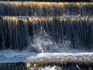 Water cascades down stone steps in golden sunlight © sablinstanislav