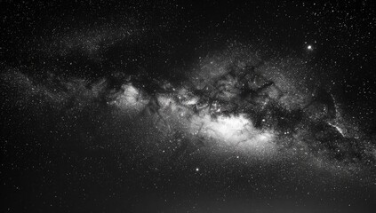 Fototapeta premium A stunning black and white photograph captures the vastness and beauty of the Milky Way galaxy stretching across a star-filled night sky.