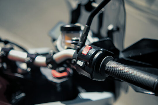 Motorcycle throttle and control detail with red switch, brake lever and reservoir showing modern mechanical design.