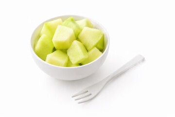 cut fresh honeydew melon cubes served in a small white ceramic bowl with a plain white fruit fork beside it healthy snack prep isolated on white background