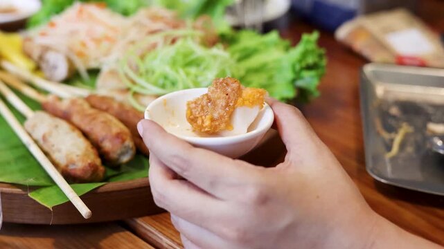 Person Holding Bowl of Dipping Sauce with Vietnamese Nem Nuong Platter