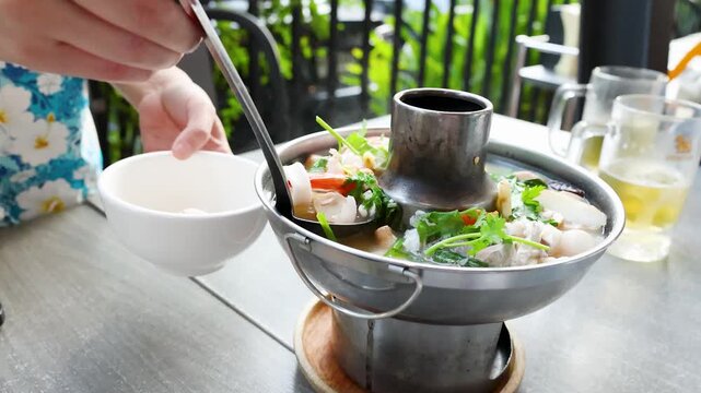 Serving Traditional Thai Tom Yum Seafood Hot Pot in a Bangkok Restaurant