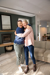 Obraz premium Diverse mature female friends hugging, standing on textured woven rug in bright living room
