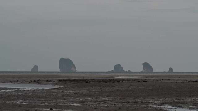 Sea stacks rise beyond low tide flats in Khlong Muang