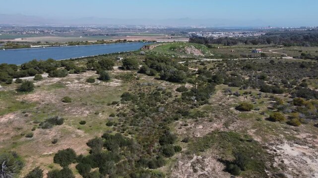 Aerial view of a wastewater treatment plant reservoir, next to a mountain of algae drying up to recover the sand and replenish it on the beach aswell as recycling the algae. Santa Pola, Spain.