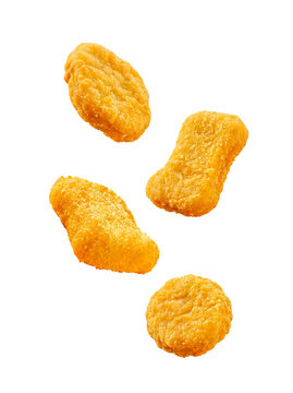 Four crispy golden chicken nuggets captured mid-air, isolated on a transparent background.