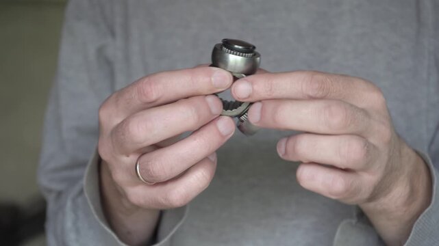Mechanic holds new tri-shaft (tripod) CV joint of car. Spare part of car transmission, bearing in hands of auto mechanic