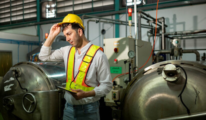 The engineer stands in front of industrial machinery, observing the process © Wosunan