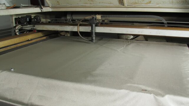 Cutter moves over shielding fabric in workshop in factory. Machine processes radio-blocking material ensuring high-quality finish for final product