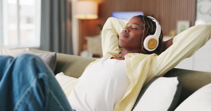 Relax, stretching and black woman with headphones on couch, audiobook chapter and calming lofi track. Chill, mindfulness podcast or person with audio tech for streaming music, listen or peace in home