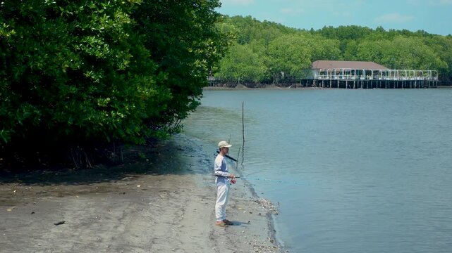Person fishing along the shore of a mangrove forest Thailand Cambodia border region