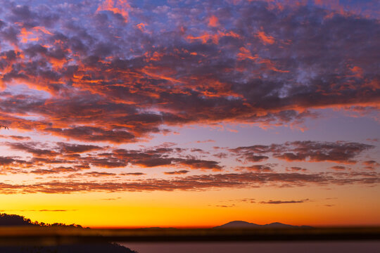 Vibrant sunset sky with fiery clouds and distant mountains