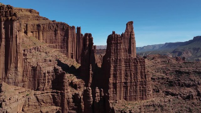 Fisher Towers' dramatic red Cutler sandstone spires near Moab, Utah, showcasing rugged canyon landscape. Aerial, Push Forward Shot