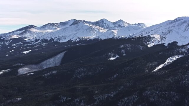 70mm zoom-in aerial drone shot of snowy peaks surrounding Dillon and Frisco near Breckenridge in Colorado's Rocky Mountains, in the dead of winter.