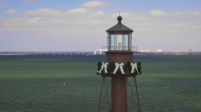 A cinematic 70mm aerial drone shot of historic Sanibel Island Lighthouse at the east end of Sanibel Island, Florida, with bright coastal shoreline near Fort Myers.