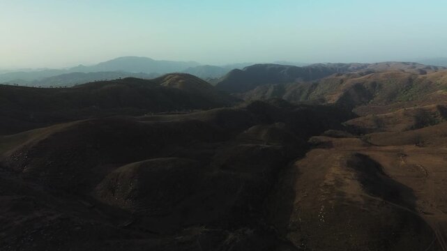 Aerial view of the Aravalli Range near Udaipur, India, with dry mountain ridges, shadowed valleys, and a vast rugged landscape under clear daylight.