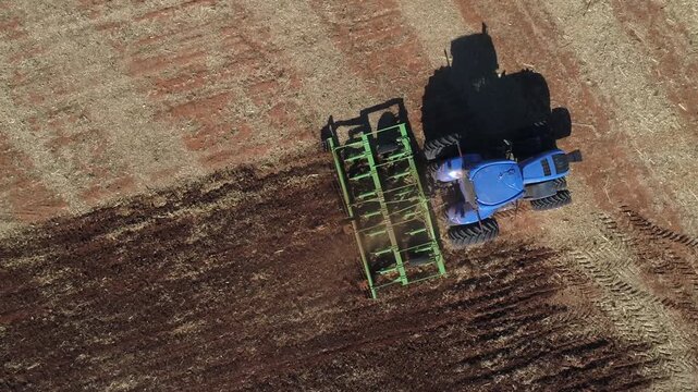 Top down aerial of tractor and field cultivator on agricultural land