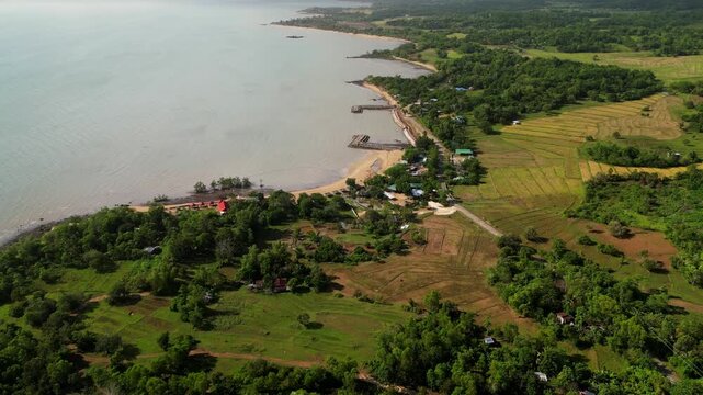 Aerial drone shot of coastal villages and farmlands stretching along the Guimaras shoreline. Perfect for travel documentaries or geographic studies.