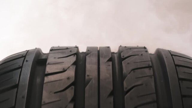 Smoke Envelops the Tire of the Car. The spinning wheel rubs against the asphalt and creates a cloud of white smoke on a white background