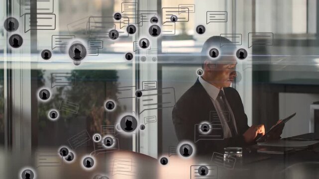 Man checking messages on tablet at business desk, causing animated icons growing across foreground