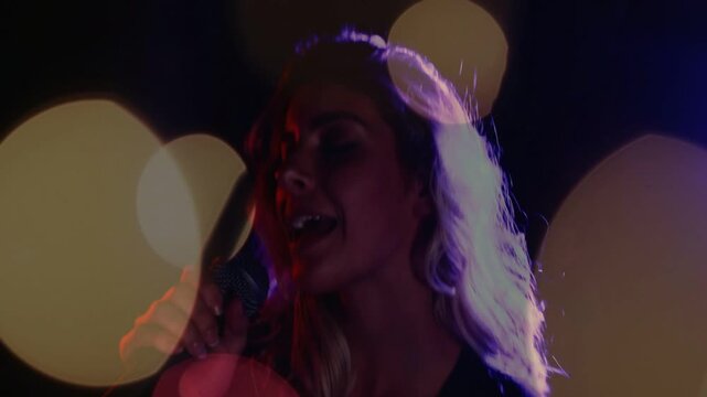 Vertical video: Singer singing with mic, camera zooming in revealing bokeh on face, boosting vocals