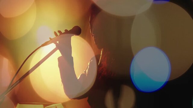 Keys playing, mic moving, musician reaching and singing, adding vocals while bokeh lights drifting