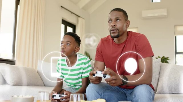 Father and son on sofa holding controllers UI mail or upload icons appearing boosting gaming focus