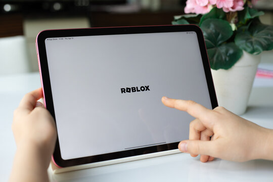 Children hands holding Apple iPad Air with multiplayer online game Roblox mobile in the screen IOS tablet