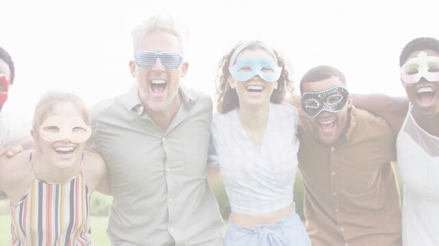 Six adults linking arms, leaning toward camera on grass, framing causing festive marketing, masked