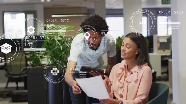 Man leaning over woman in office checking tablet, HUD icons appearing while closing finance orders